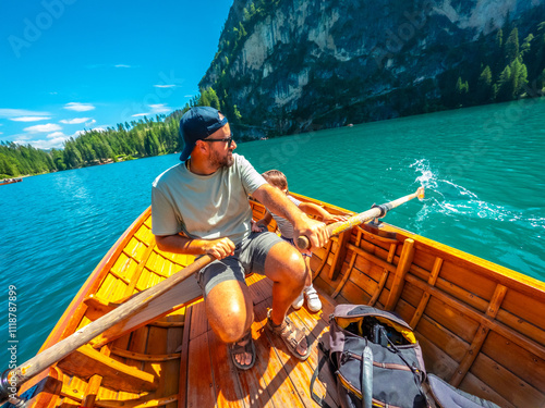 Father and son rowing on lake braies in the italian dolomites photo