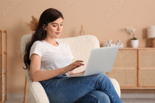 Beautiful young woman with laptop on sofa in living room