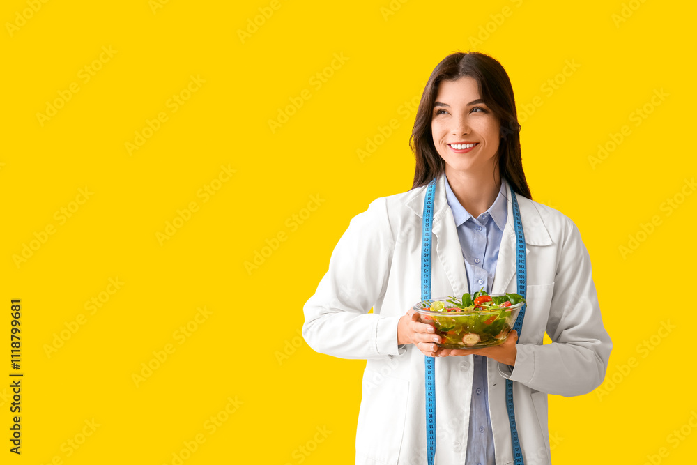Female nutritionist with vegetable salad on yellow background Female nutritionist with vegetable salad on yellow background