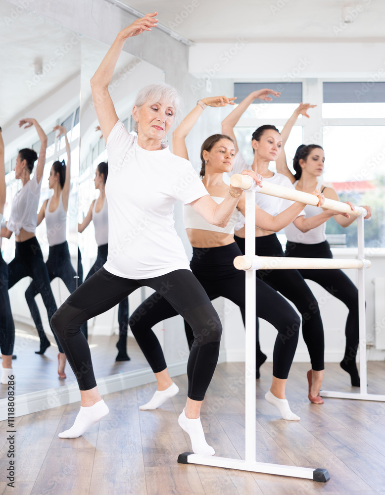 Young women student of ballet school near ballet bare performs composition with grand plie with participation of experienced mature female mentor. Training program for members of ballet troupe of Young women student of ballet school near ballet bare performs composition with grand plie with participation of experienced mature female mentor. Training program for members of ballet troupe of