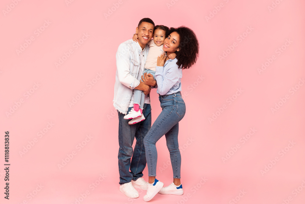 Happy family of three with little girl on hands embracing, loving black parents and cute child posing over pink studio background, full length shot Happy family of three with little girl on hands embracing, loving black parents and cute child posing over pink studio background, full length shot