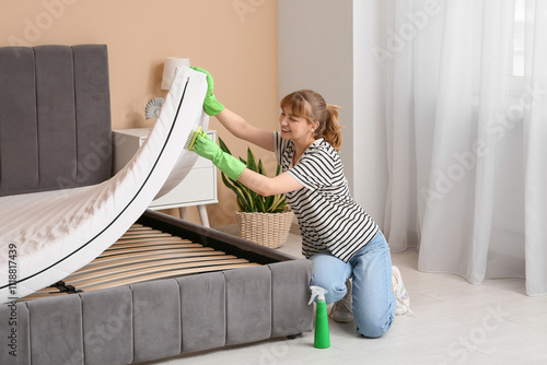 Young woman cleaning mattre...