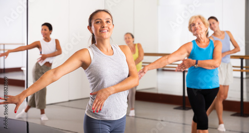 Latino girl dancing modern dance in fitness studio with other dancers