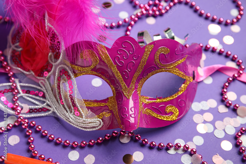 Beautiful pink carnival mask with decor on lilac background. Closeup Beautiful pink carnival mask with decor on lilac background. Closeup