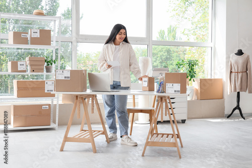 Pregnant seller with notebook and parcels working in online store warehouse