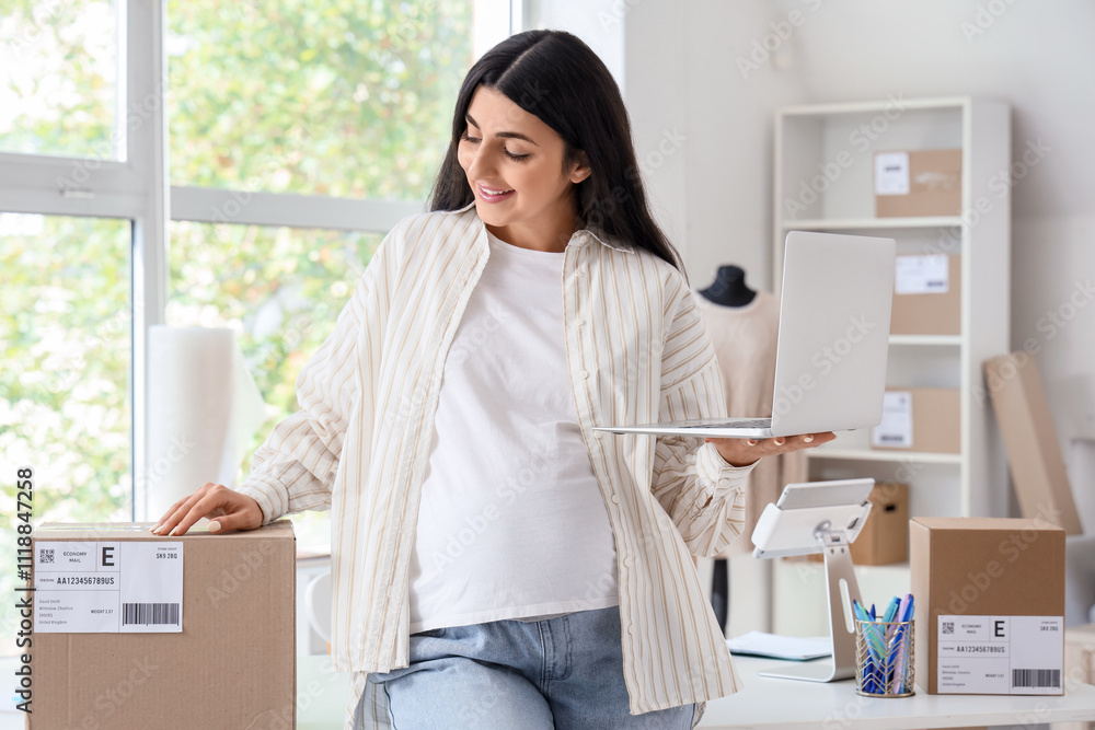Pregnant seller with laptop and parcel in online store warehouse Pregnant seller with laptop and parcel in online store warehouse