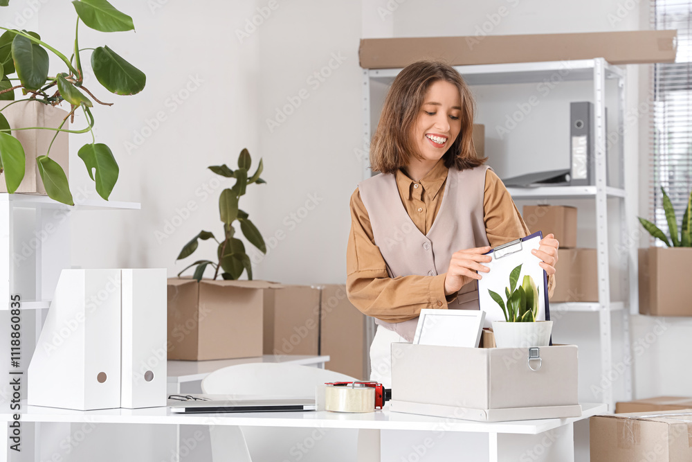 Young businesswoman packing things in office on moving day Young businesswoman packing things in office on moving day
