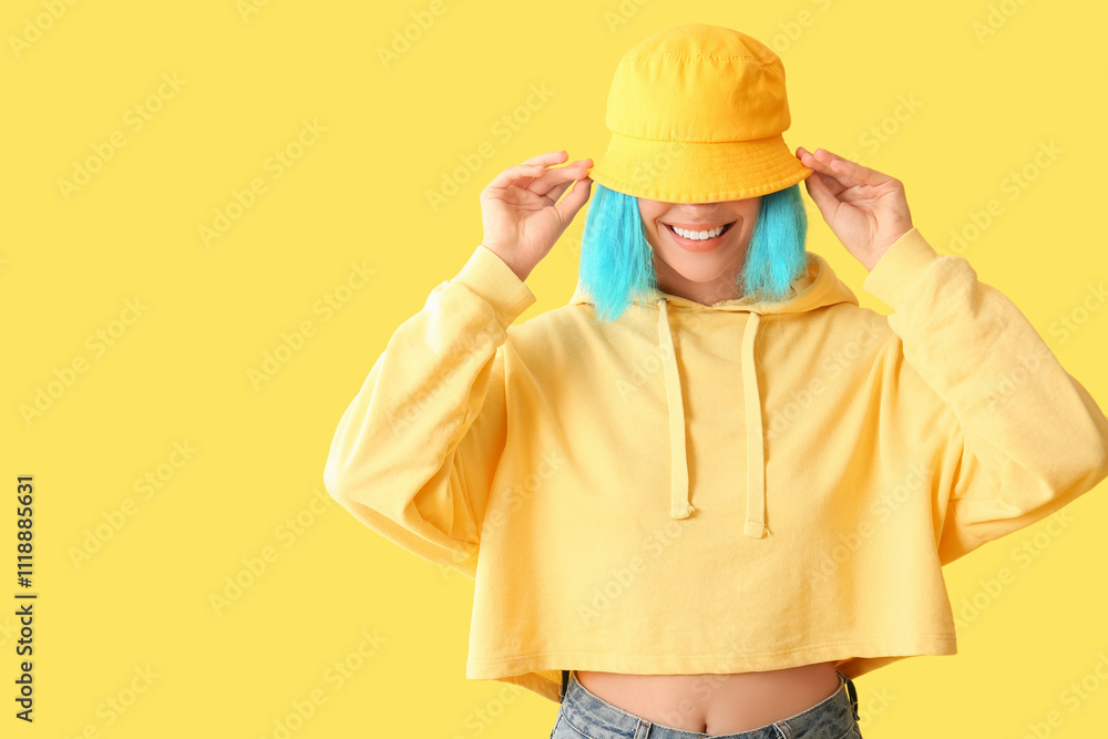 Beautiful young woman in blue wig and stylish panama on yellow background Beautiful young woman in blue wig and stylish panama on yellow background