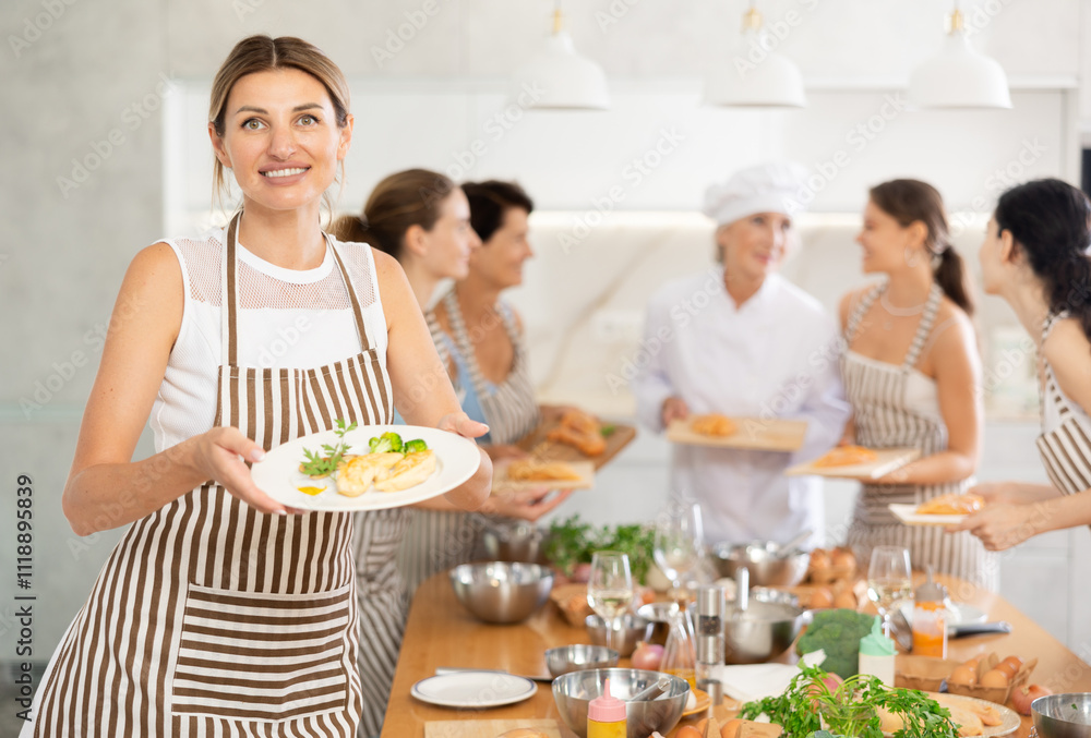 Young girl visiting culinary school holds plate with cooked chicken fillet in hands, successful result of studies Young girl visiting culinary school holds plate with cooked chicken fillet in hands, successful result of studies