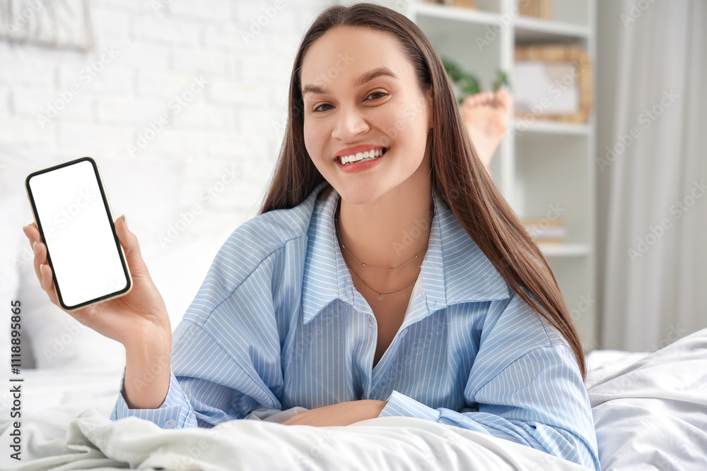 Young woman with blank mobile phone lying in bedroom Young woman with blank mobile phone lying in bedroom