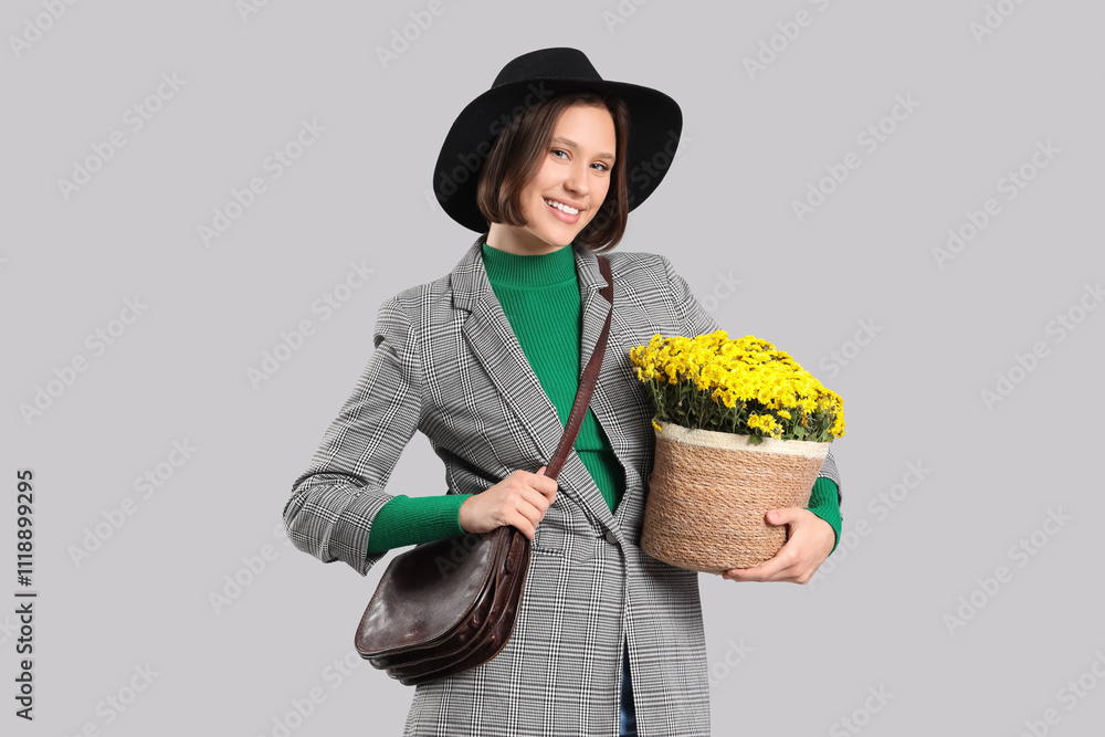 Stylish young woman with yellow chrysanthemum flowers on light background Stylish young woman with yellow chrysanthemum flowers on light background