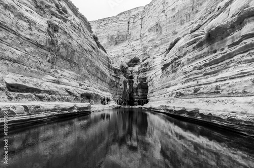 A black and white photo of a river with a cliff in the background