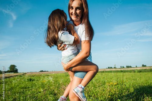 Loving mother plays with daughter, hugs and kisses