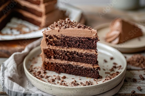 A slice of chocolate cake with frosting and chocolate shavings.