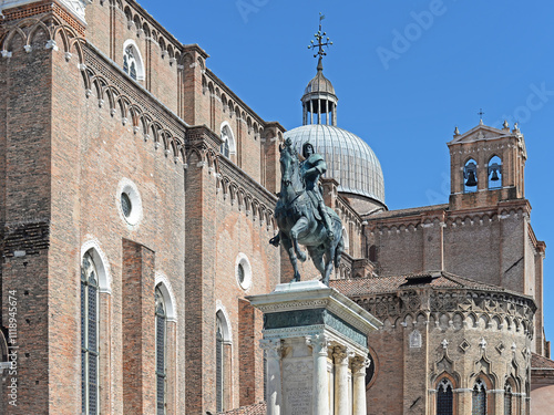 Statue of Bartolomeo Colleoni and church of Santi Giovanni e Paolo with dome and bell tower on a summer day with clear blue sky in Venice, Italy