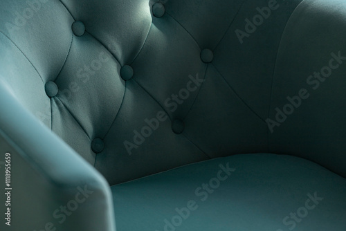 Close-up of a soft blue velour armchair with carriage upholstery in the shadows and rays of the sun with copy space.