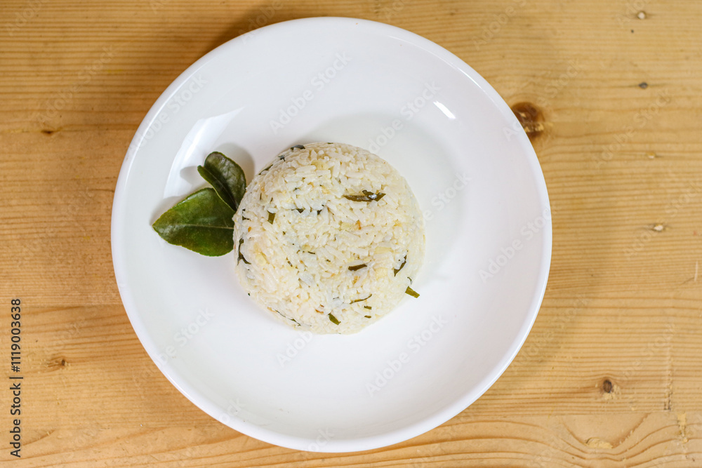 Lime leaf rice on wooden table. Fried onion on top. thisi is Indonesian cuisine on rattan plate. Nasi daun jeruk Lime leaf rice on wooden table. Fried onion on top. thisi is Indonesian cuisine on rattan plate. Nasi daun jeruk