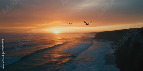 A shot of birds flying gracefully over the ocean from the cliffside during sunset, with the sky filled with rich colors and the waves below gently rolling in.  photo