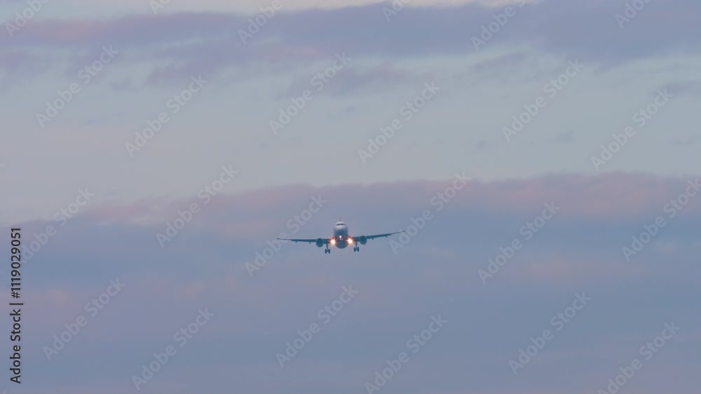 Long shot of unknown aircraft with headlights on descending approaching landing Long shot of unknown aircraft with headlights on descending approaching landing