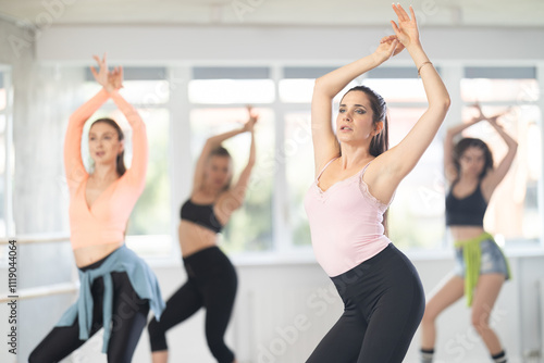 Adult woman rehearsing modern high heels dance in group in studio