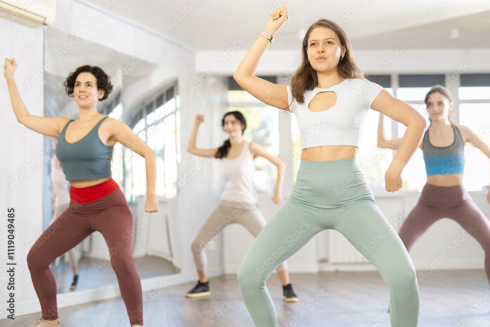 Fototapeta premium Young female coach conducts classes in modern energetic hip hop dancing for female company group. Concept of active hobby, pleasant way to lose weight and maintain perfect figure