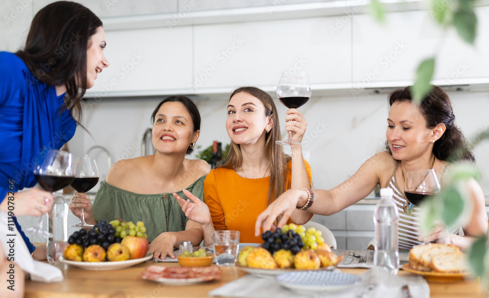 Girlfriends drinking wine and having conversation over dinner at a house party Girlfriends drinking wine and having conversation over dinner at a house party