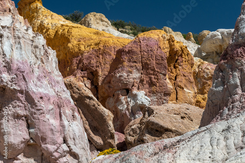 Paint Mines Park in Colorado. Colorful sedimentary rock formations exhibit vibrant hues of yellow, pink, and white in a striking geological landscape during bright daylight hours photo