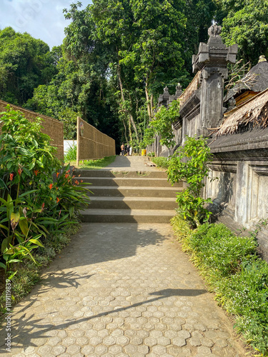 stone path and stairs leading into the village of Panglipuran Bali decorated with green trees on the right and left photo