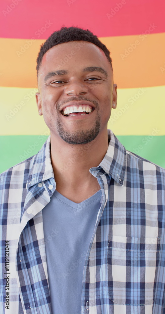 Vertical image of portrait of happy african american man holding lgbt rainbow flag Vertical image of portrait of happy african american man holding lgbt rainbow flag