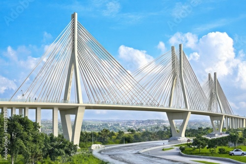 A modern cable-stayed bridge with a scenic backdrop and clear blue sky.