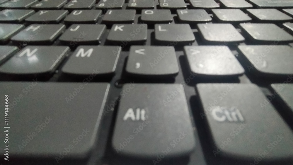 A black laptop keyboard with white lettering, placed on a wooden surface.. A black laptop keyboard with white lettering, placed on a wooden surface..