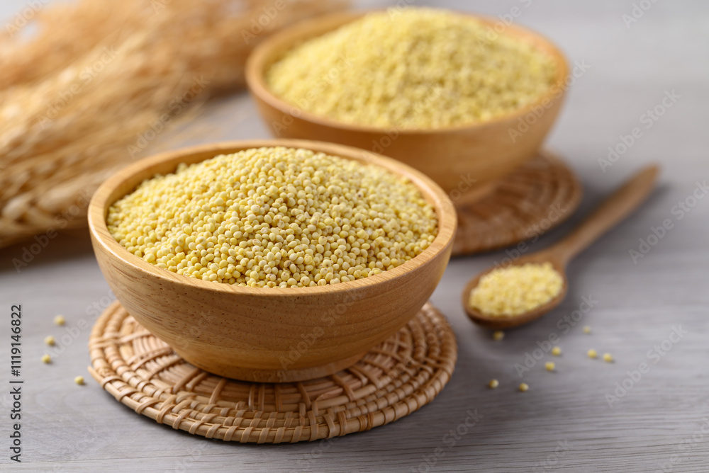 Organic yellow millet grain in wooden bowl with spoon on white table, Healthy food ingredient Organic yellow millet grain in wooden bowl with spoon on white table, Healthy food ingredient