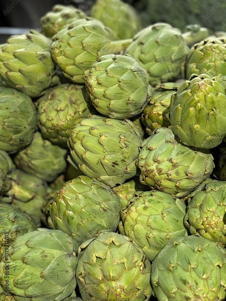 A pile of many fresh, green artichokes showcased in a market setting, highlighting their texture and natural vibrancy. Perfect for themes of organic produce and healthy living. A pile of many fresh, green artichokes showcased in a market setting, highlighting their texture and natural vibrancy. Perfect for themes of organic produce and healthy living.