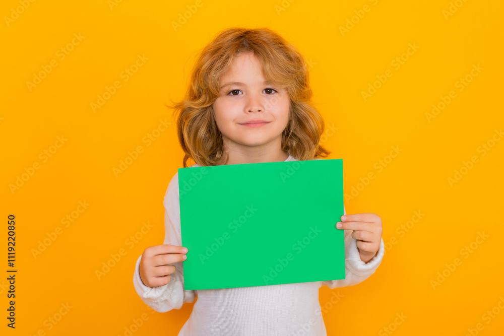 Kid showing empty sheet of paper on yellow background. Portrait of a kid holding a blank placard, poster. Kid showing empty sheet of paper on yellow background. Portrait of a kid holding a blank placard, poster.