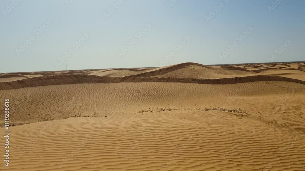 Wind blowing sands over the dunes in the Sahara desert in Tunisia on a hot and sunny day Wind blowing sands over the dunes in the Sahara desert in Tunisia on a hot and sunny day