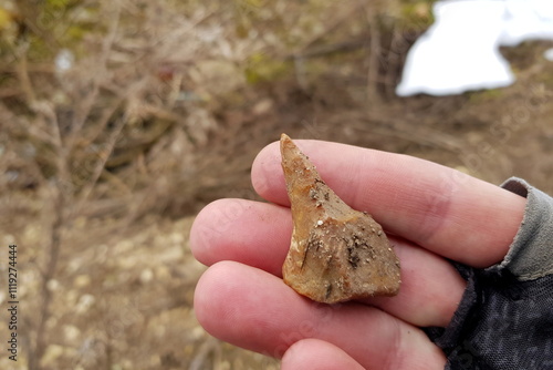 Flint puncture found in the ground, stone age tool in hand, field photo photo