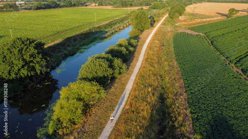Aerial view of cyclist using canal towpath in low sun 