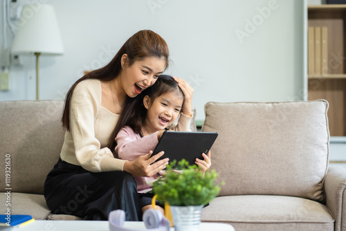 Mother and daughter spend their holiday in the living room at home, daughter kissing happy mother.