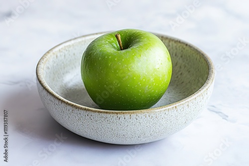 Green apple in ceramic bowl on marble surface photo