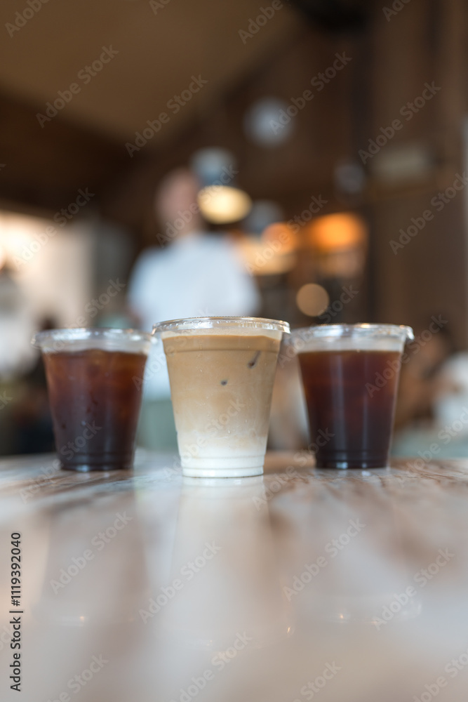 Close up view a glass of ice latte placed on the center between ice black coffee, desk blurred background, drink beverage Close up view a glass of ice latte placed on the center between ice black coffee, desk blurred background, drink beverage
