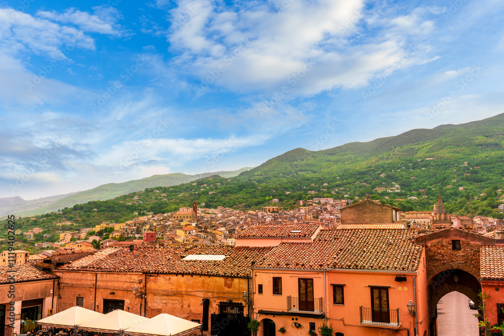 Obraz premium beautiful travel landscape of old european town with ancient church and vintage roofs in mediterranean style with amazing view to great green mountain and nice blue cloudy sky on background