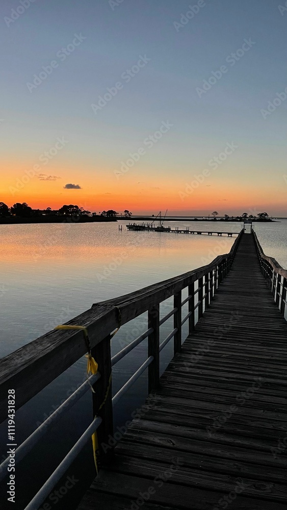 Fototapeta premium Serene sunset over calm lake with pier.