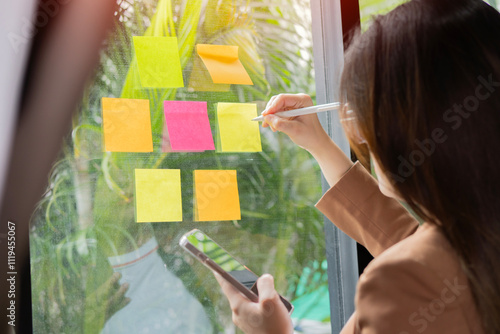 Young creative team use post it notes to share idea sticky note on glass wall.