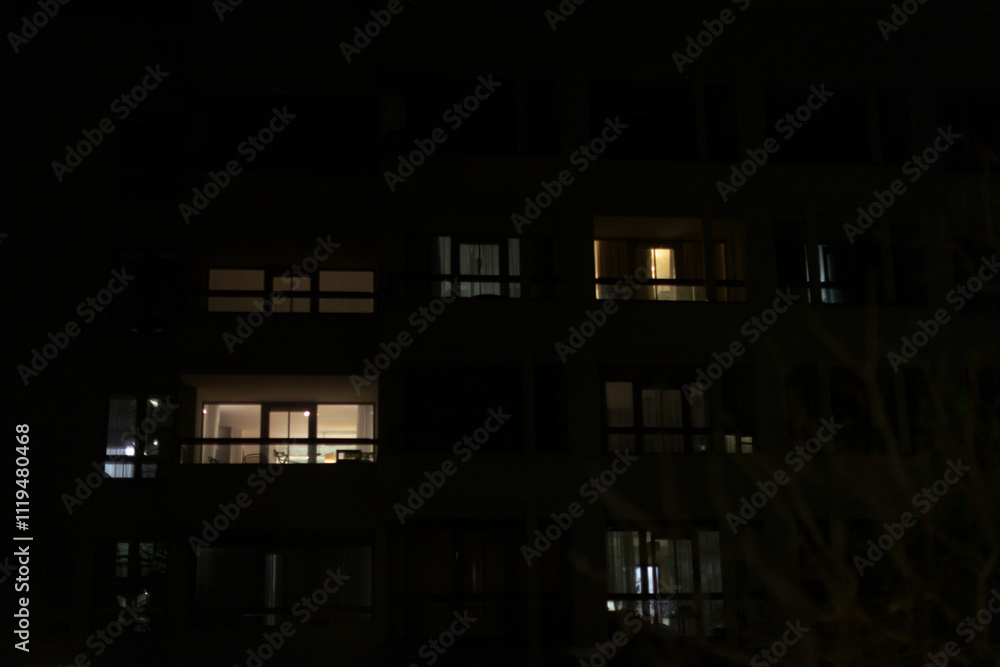 A large building featuring numerous windows is beautifully lit up at night A large building featuring numerous windows is beautifully lit up at night