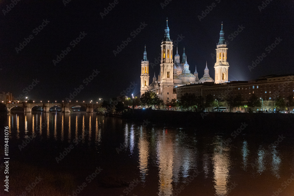 Impressive panoramic view of the Basilica del Pilar at night illuminated and with its reflection on the river Ebro in Zaragoza Aragon. Impressive panoramic view of the Basilica del Pilar at night illuminated and with its reflection on the river Ebro in Zaragoza Aragon.