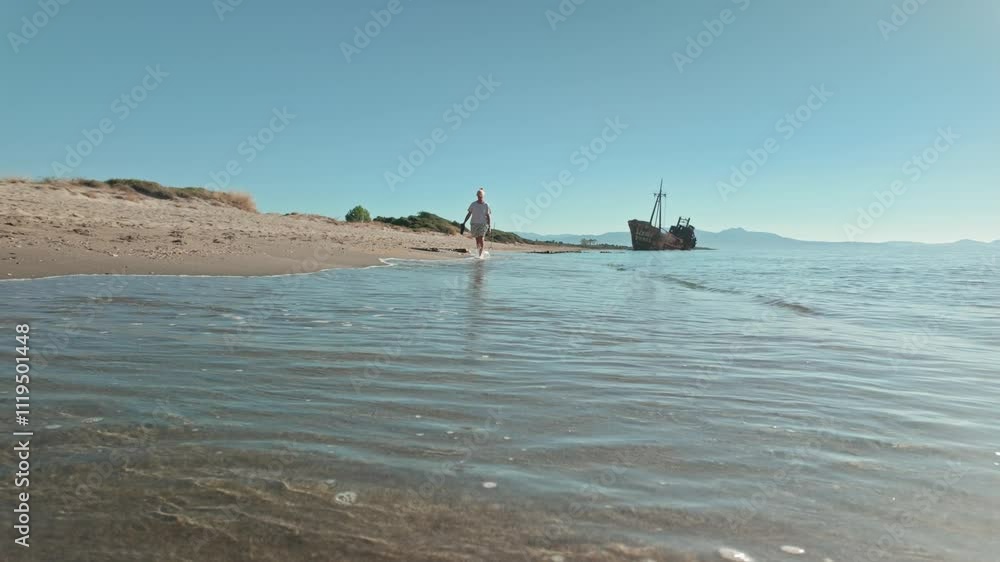 Woman walks along Mediterranean shore from Dimitrios shipwreck LOW ANGLE Woman walks along Mediterranean shore from Dimitrios shipwreck LOW ANGLE