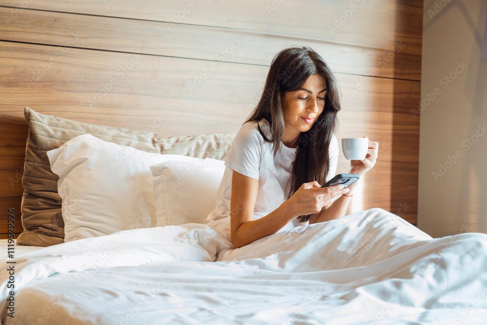Young Woman drinking coffee in the bed using her phone Young Woman drinking coffee in the bed using her phone