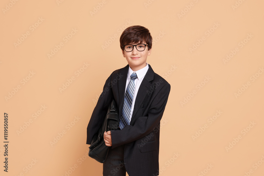 Boy in suit pretending to be businessman on beige background. Dreaming of future profession Boy in suit pretending to be businessman on beige background. Dreaming of future profession