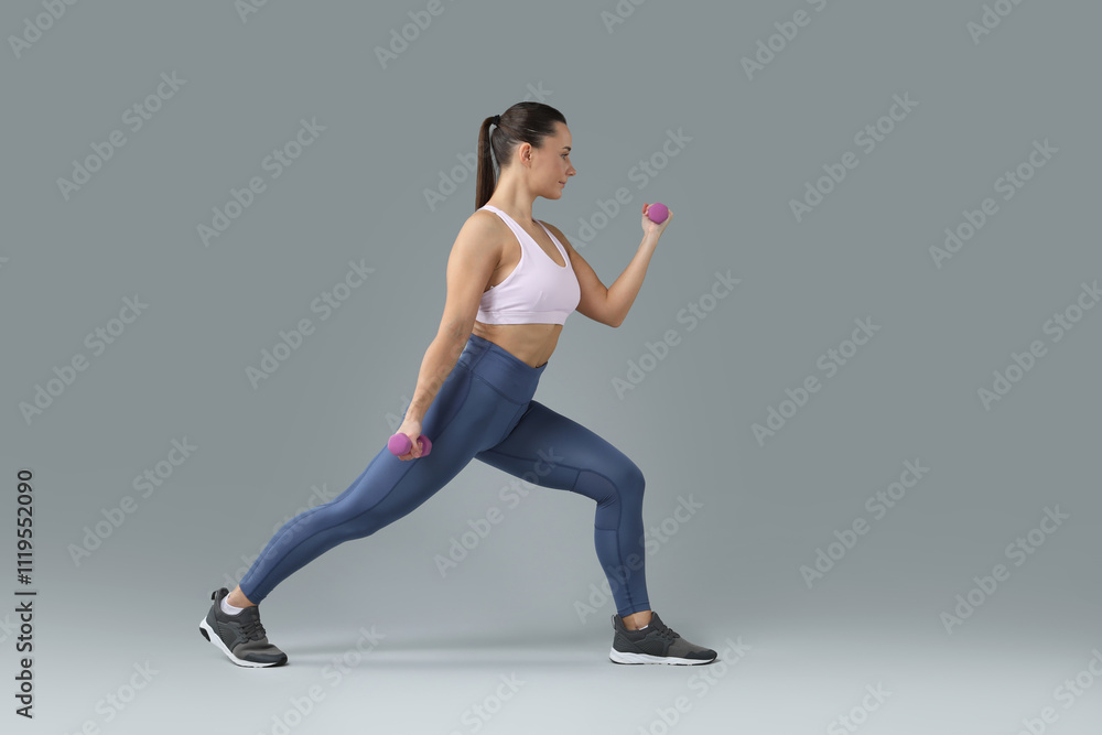Fototapeta premium Woman exercising with dumbbells on light grey background, space for text