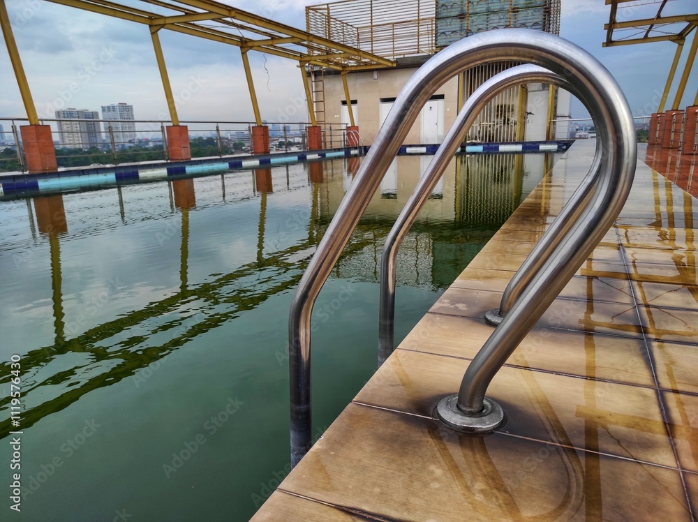Swimming pool with aluminum roof frame shadow in unused swimming pool, murky green water. Swimming pool is on top of the building. Abandoned swimming pool Swimming pool with aluminum roof frame shadow in unused swimming pool, murky green water. Swimming pool is on top of the building. Abandoned swimming pool